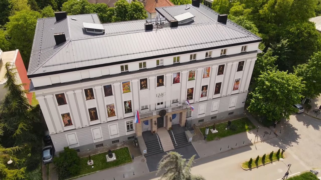 Zgrada Galerije Matice srpske u Novom Sadu okružena zelenilom.